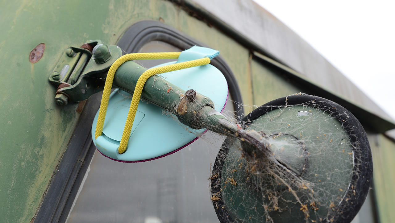 Blue UE Roll mobile speaker strapped to a rear view mirror